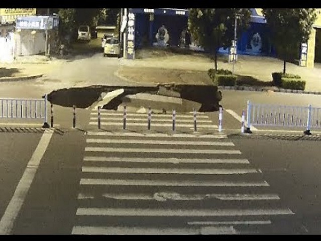 バイクの男性、大きな穴に吸い込まれる（画像は『CCTV+　2017年8月18日公開 YouTube「Eyes-off-road Motorcyclist Crashes into Street Cave in」』のサムネイル）