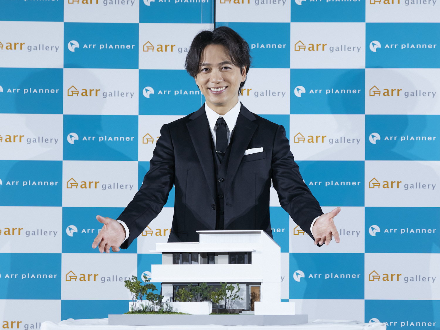 発表会で理想の家の模型を前に笑顔の山崎育三郎