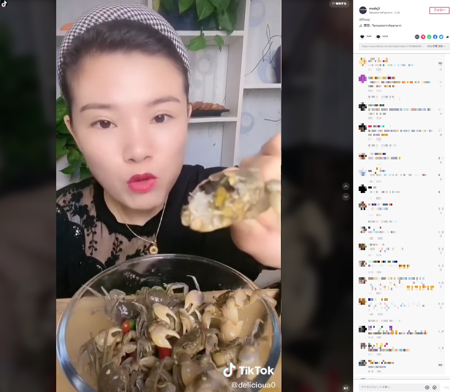 半分になったカニを見せる女性（画像は『โลกแห่งการกินอาหาร　2022年5月26日付TikTok「มีชีวิตอยู่」』のスクリーンショット）