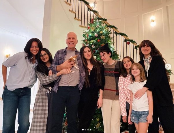 クリスマスツリーの前で寄り添うブルースと家族達（画像は『Demi Moore　2022年12月13日付Instagram「We are FAMILY!!」』のスクリーンショット）
