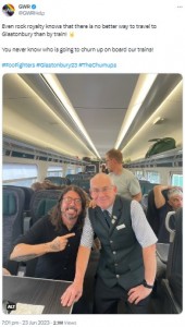 座席に座り、鉄道職員と写真撮影に応じるデイヴ・グロール。右側後方の座席には「フー・ファイターズ」のギタリスト、パット・スメアも写っている（画像は『GWR　2023年6月23日付Twitter「Even rock royalty knows that there is no better way to travel to Glastonbury than by train!」』のスクリーンショット）