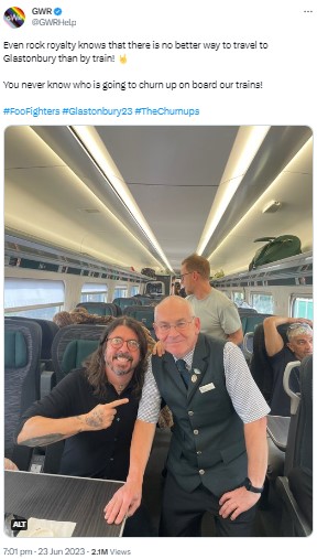 座席に座り、鉄道職員と写真撮影に応じるデイヴ・グロール。右側後方の座席には「フー・ファイターズ」のギタリスト、パット・スメアも写っている（画像は『GWR　2023年6月23日付Twitter「Even rock royalty knows that there is no better way to travel to Glastonbury than by train!」』のスクリーンショット）