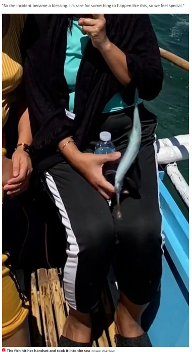 スロー再生で確認すると、海面から飛び跳ねたトビウオがネレッサさんの手元にぶつかり、手に持っていたスマホは海の中に落ちてしまった（画像は『The Daily Star　2023年7月12日付「Flying fish leaps onto boat and steals woman’s phone as she poses for a pic」（Image: ViralPress）』のスクリーンショット）