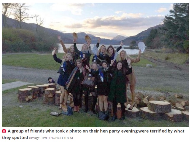 女性10人の他にもう1人、知らない人物が…。女性たちの少し背後に、切り株の横にうずくまって彼女たちを見上げる小さな男の子の姿がある（画像は『The Daily Star　2023年8月8日付「Hen party flees Scottish beauty spot after haunting group photo unearths lake tragedy」（Image: TWITTER/HOLLYDCA）』のスクリーンショット）