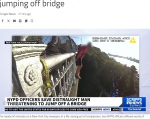 サンダル履きで10センチほどのコンクリートの上に立ち、両手で欄干を持つことでかろうじて身体を支えている男性。説得は約40分に及んだ（画像は『KULR8.com　2023年10月20日付「NYPD officers hailed as heroes for saving man from jumping off bridge」』のスクリーンショット）