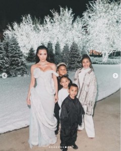 自宅豪邸の庭で並ぶキムと4人の子ども達。数本のクリスマスツリーとライトアップされた木々が並んでいる（画像は『Kim Kardashian　2023年12月26日付Instagram「Christmas 2023」』のスクリーンショット）