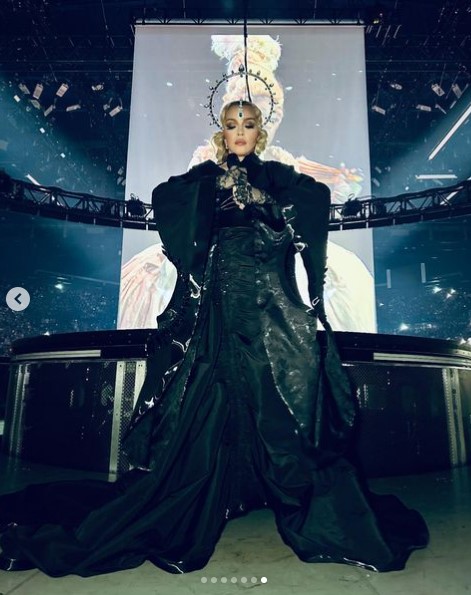 ワシントンD.C.公演のステージに立つマドンナ。黒い衣装に身を包み、頭には大きなヘッドピースをつけている（画像は『Madonna　2023年12月19日付Instagram「It’s Show-Time………….」』のスクリーンショット）