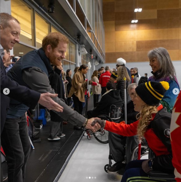 カナダ訪問最終日、バンクーバーで競技者と握手するヘンリー王子。奥にはベージュのコートを着たメーガン妃が見える（『Invictus Games Foundation　Instagram「Thank you to our amazing hosts at Hillcrest Centre for introducing us to the wonderful world of curling.」』より）